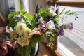 An amazing bouquet of diferent colourful flowers standing near the window.