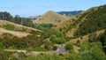 Amazing bush covered hills and grasslands surround winding countryside road.