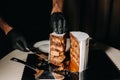 Amazing Cakes. A black-gloved chef is slicing a chocolate wedding cake. The wedding Cake is delicious inside on a black background Royalty Free Stock Photo