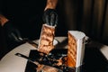 Amazing Cakes. A black-gloved chef is slicing a chocolate wedding cake. The wedding Cake is delicious inside on a black background Royalty Free Stock Photo