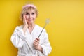 Amazing charming elderly woman in bathrobe wearing crown on head, holding magica wand in hands, fairy Royalty Free Stock Photo