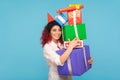 Amazing charming hipster woman with fancy red hair and party cone on head holding lot of gift boxes