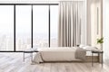 Amazing city view from floor-to-ceiling window in sunny stylish bedroom with parquet, modern bed and wooden bedside tables. 3D