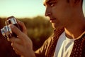 Amazing close up portrait of handsome young man with vintage camera,on a meadow background. Travel mood. Photography.