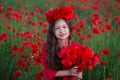 Amazing close up portrait of lovely cute young romantic girl with poppy flower in hand posing on field background. Wearing red Royalty Free Stock Photo