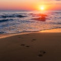 Amazing colorful sunrise at sea, footprints in the sand Royalty Free Stock Photo