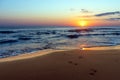 Amazing colorful sunrise at sea, footprints in the sand Royalty Free Stock Photo