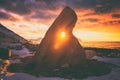 Amazing colors of north atlantic sunset, winter landscape with shining sun through a hole in bizarre stone, majestic cloudy sky