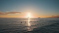 Amazing colors of a tropical sunset. Silhouettes of sailing boats floating on the ocean horizon. Surfers ride the waves Royalty Free Stock Photo