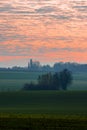 A magical scenery with an amazing colourful sunrise with clouds attached like dots to the sky and the dew over the agricultural fi