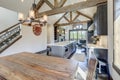 Amazing dining room near modern and rustic luxury kitchen with vaulted ceiling and wooden beams, long island with white quarts Royalty Free Stock Photo