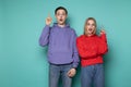 Amazing emotional young couple friends in casual clothes posing with open mouth pointing up with fingers