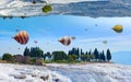 Fantastic unreal world, hot air balloons fly in blue sky between white Pammukale travertines, Turkey