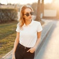 Amazing fashionable young hipster woman in stylish summer clothes is standing and posing at sunset of summer. Attractive girl. Royalty Free Stock Photo