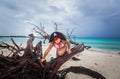 Amazing funny, serious little girl pirate sitting on old dead tree at the beach against dark dramatic sky and ocean background