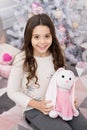 Amazing gift for play and sleep next to. Happy child got gift for xmas. Little girl hold soft toy gift at Christmas tree