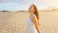 Amazing girl in desert at sunset. Beautiful young fashion woman in white dress breathing enjoying relaxing on the beach Royalty Free Stock Photo