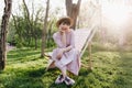 Amazing girl with short dark hair sitting on garden chair with legs crossed on wonderful nature background. Portrait of Royalty Free Stock Photo