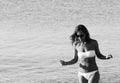 Amazing girl with sunglasses in a white swimsuit  walking on the rocky beach. Apulia, Salento, Italy Royalty Free Stock Photo