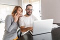 Amazing happy young loving couple sitting at the kitchen using laptop computer Royalty Free Stock Photo