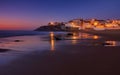 Amazing landscape of the Atlantic ocean coast at dusk. Night view on the village in lights, reflecting on a sandy beach. Portugal.