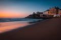 Amazing landscape of the Atlantic ocean coast at sunset. View of colorful dramatic sky and buildings near a sandy beach. Long expo Royalty Free Stock Photo