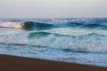 Amazing landscape on the Atlantic ocean at sunrise. View of foamed waves running ashore sandy beach. Concept of nature background. Royalty Free Stock Photo