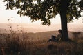 Amazing landscape, young girl with book sitting under big tree, colorful forest on the background Royalty Free Stock Photo