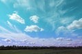 Amazing light blue and purple sky with clouds over green meadow and trees Royalty Free Stock Photo