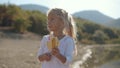 Amazing little girl eating a banana near the lake