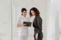 Amazing looking two nurses at the medical clinic meeting on the corridor and discussing about program of work while Royalty Free Stock Photo