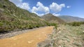 Amazing mountain landscape with a dirty stormy river. Panorama of a green mountain valley. Green hills, blue sky and white clouds Royalty Free Stock Photo