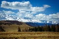 Amazing mountain landscape. Rocky mountains with snowy peaks, hills covered with grass in the Alpine scene on a bright sunny day Royalty Free Stock Photo