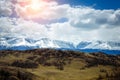 Amazing mountain landscape. Rocky mountains with snowy peaks, hills covered with grass in the Alpine scene on a bright sunny day Royalty Free Stock Photo