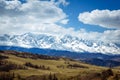 Amazing mountain landscape. Rocky mountains with snowy peaks, hills covered with grass in the Alpine scene on a bright sunny day Royalty Free Stock Photo