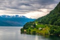 Amazing nature view with dramatic sky and wooden houses on the banks of the Norwegian fjord.  Scandinavian Mountains, Norway. Royalty Free Stock Photo