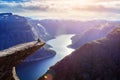 Amazing nature view with Trolltunga and a man sitting on it at sunset. Location: Scandinavian mountains, Norway, Odda. Royalty Free Stock Photo