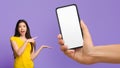 Amazing Offer. Excited Asian Woman Pointing At Blank Smartphone In Huge Hand