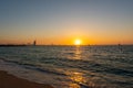 Amazing orange sunset at the beach in Dubai. Beautiful orange colors coming from sun and reflect over Gulf sea waves and shore of Royalty Free Stock Photo