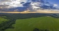 Panoramic view of cloudy sky with sun rays over green field and forest Royalty Free Stock Photo