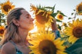 Amazing photo, beautiful young blonde woman standing among sunflowers with cloed eyes, bent a sunflower to her face Royalty Free Stock Photo