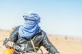 Amazing portrait of Bedouin man on his motorbike driving through Sahara Desert