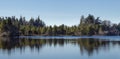 Tree reflections on the smooth clear waters of Cranberry Lake at Deception Pass, Washington.