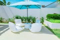 Relaxing inviting view of luxury outdoor backyard furniture with blue great umbrella and comfortable white beautiful chairs