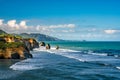 Thee three sisters on Tongaporutu beach lined by huge cliffs and the volcanic mountain in the background