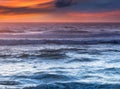 Amazing romantic seascape of ocean coastline at sunset. Landscape of colorful cloudy sky and foamy waves.