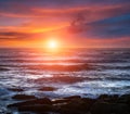 Amazing romantic seascape of ocean coastline at sunset. Landscape of colorful cloudy sky and foamy waves.