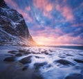 Amazing sandy beach with stones in blurred water at sunset