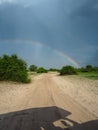 Amazing scene of double rainbow on blue sky copy space background above natural sand route through green savanna plain