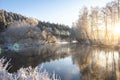 Winter landscape of sunrise near lake and hoarfrost on the branches